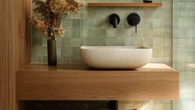 Remodeled bathroom with sage green tiles and oak vanity